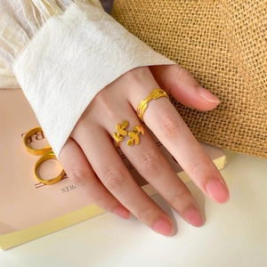Detail of 18K gold plated titanium leaf and striped open rings on a female hand