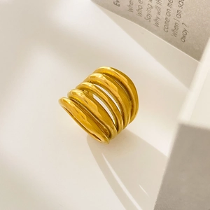 Close-up of multilayered gold-plated wrap ring on a minimalist white geometric background