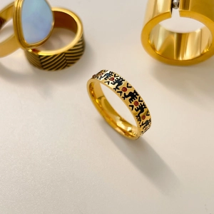 Close-up of gold ring with black enamel figures and red dots in vintage style