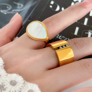 Detail of 18K gold plated ring with teardrop shell inlay and wide geometric steel band