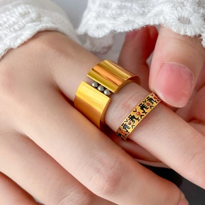 Close-up of 18K gold plated titanium rings with steel beads and black enamel engravings