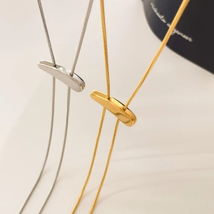 Macro shot of minimalist gold and silver snake chain necklaces with sleek metal sliders