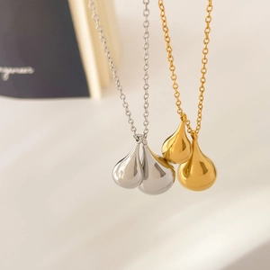 Macro shot of polished water drop pendants in gold and silver finish with smooth metal surface