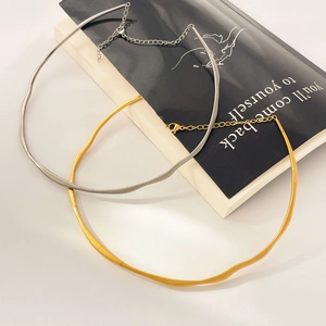 Detail view of wavy hammered metal torque necklaces in gold and silver finish with lobster clasp