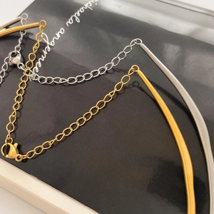 Detail of gold and silver snake bone necklaces with lobster clasps on a black card