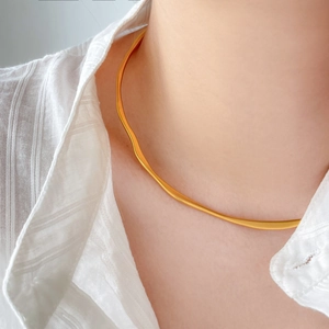 Macro view of gold-plated snake bone chain necklace showing smooth metallic texture