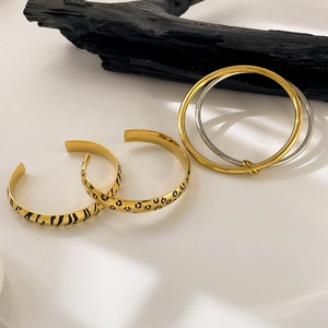 Detail of leopard and zebra pattern bangles with polished gold and silver rings