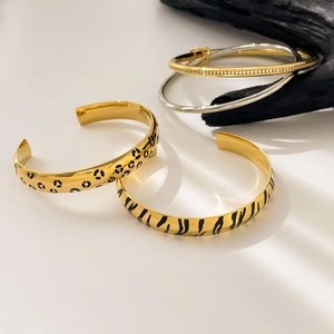 Detail of leopard print and striped 18K gold plated stackable titanium steel bangles