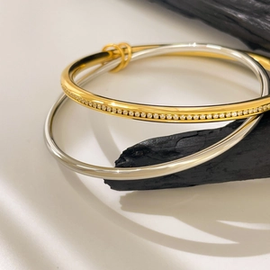 Detail of 18K gold and silver stacked bracelets with pavé diamonds on textured wood
