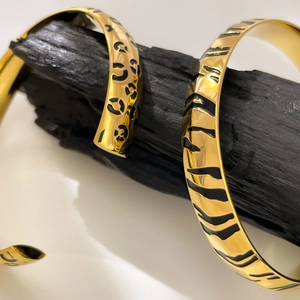 Detailed close-up of 18K gold plated titanium bangles with leopard and tiger patterns