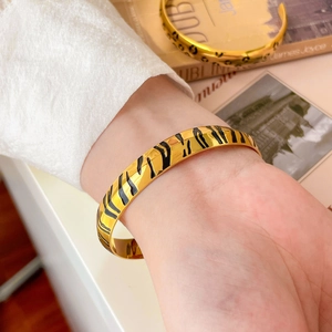 Close-up of golden tiger stripe bangle with 18K gold plating on female wrist