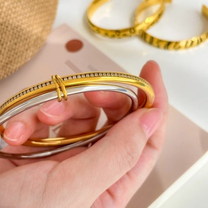 Stacked 18K gold and silver leopard pattern bangles with micro-pave crystals on wrist