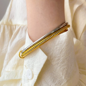 Close-up of dual-layer gold and silver bracelets with cubic zirconia on a linen cuff