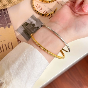 Detail of 18K gold and silver stacked bangles with sparkling crystals on model's wrist