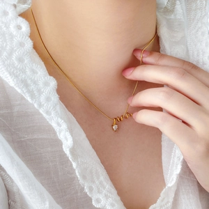 Artistic gold snake twist necklace with teardrop zircon pendant worn on neckline