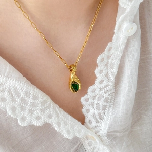 Close-up of teardrop green zircon pendant necklace on a gold paperclip chain
