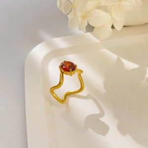 Détail d'une bague plaquée or 18K avec anneau ondulé et zircon rouge ovale