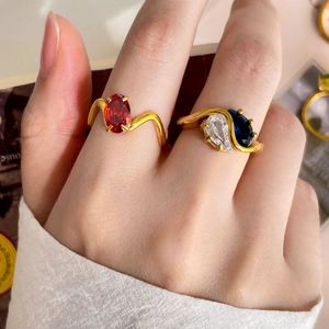 Deux bagues dorées ondulées avec zircon rouge ovale et pierre bleue en forme de cœur