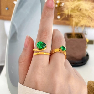 Détail de bagues plaquées or 18K avec zircons verts tailles poire et ronde portées au doigt