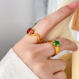 Détail de bagues en titane plaqué or 18K avec zircons rouges et verts sur la main