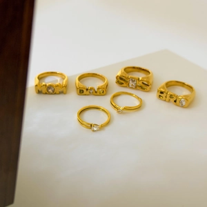 Detail of 18K gold-plated rings with MOM DAD SIS BRO letters and sparkling zircons