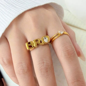 Detailed close-up of wide gold ring with BRO lettering and marquise-cut zircon