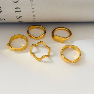 Detail of 18K gold plated wavy and multi-layer rings set on lifestyle prop paper
