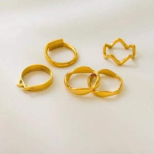 Set of four 18K gold plated wavy and geometric stacking rings on white background