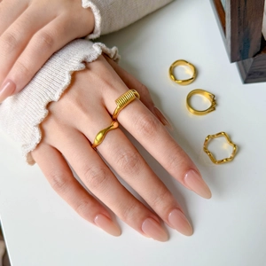 Detailed view of five 18K gold plated wavy and multi-layered stackable rings for women