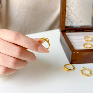 Polished 18K gold-plated wave ring with geometric mountain peaks on a model hand
