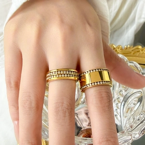 Détail de bagues superposées en titane plaqué or 18K avec sertissage pavé de zircons