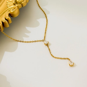 Vue détaillée d'un collier en Y doré orné de zircons en forme de goutte d'eau sur blanc