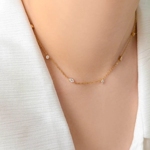 Gros plan d'un collier en acier titane doré orné de délicats pendentifs en zircon