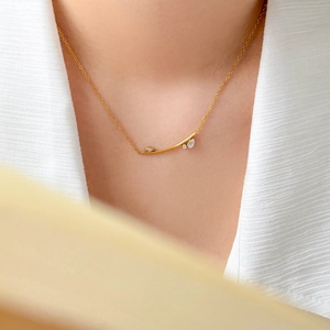 Collier minimaliste en tube doré avec zircons porté par un mannequin élégant