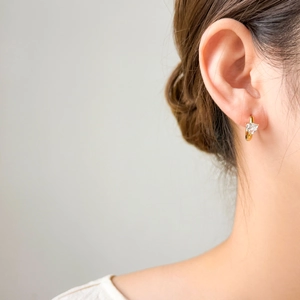 Close-up of heart-shaped zircon earrings in 18K gold plating worn by a model