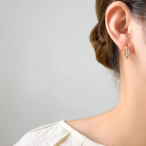 Detailed view of 18K gold plated titanium hoop earring with three clear zircons on ear