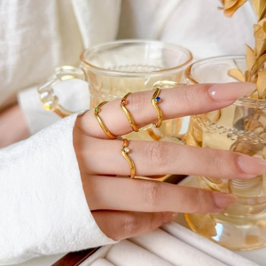 Set of 4 wavy 18K gold plated rings with colorful cz stones in a lifestyle setting
