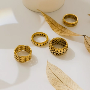 Close-up of four gold hollow geometric rings featuring honeycomb and woven mesh patterns