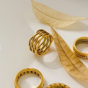 Detailed view of 18K gold plated titanium rings with hollow geometric patterns and weaving