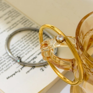 Detail of minimalist gold bracelet with round zircon and a sleek silver bangle