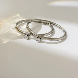 Detail view of oval polished steel bangles with clear round zircon in four-prong setting