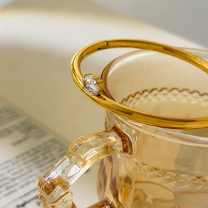 Close-up of gold bangle with round cubic zirconia against vintage glass background