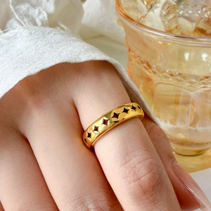 Detailed view of an 18K gold plated hollow star pattern ring worn on a finger