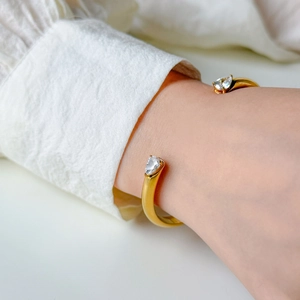 Close-up of 18K gold-plated bangle with sparkling pear-cut zircon stones on model's wrist