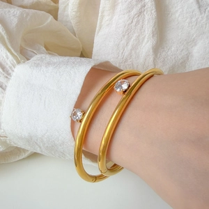 Detail of two 18K gold plated bangles with round cubic zirconia on a model wrist