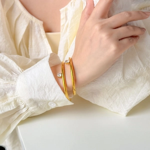Set of two gold-plated bangles with clear round zircon stones worn by a model