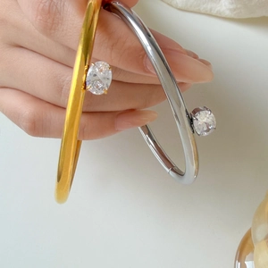 Detail of gold and silver slim bangles with large round claw-set cubic zirconia stones