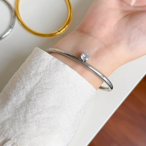 Close-up of silver-toned zircon cuff bracelet featuring a round-cut gemstone on model wrist