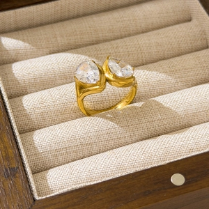 Close-up of golden Toi et Moi ring with dual pear-cut stones in a jewelry box