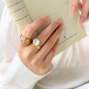 Detail of 18K gold plated thick rings featuring large emerald and oval cut cubic zirconia